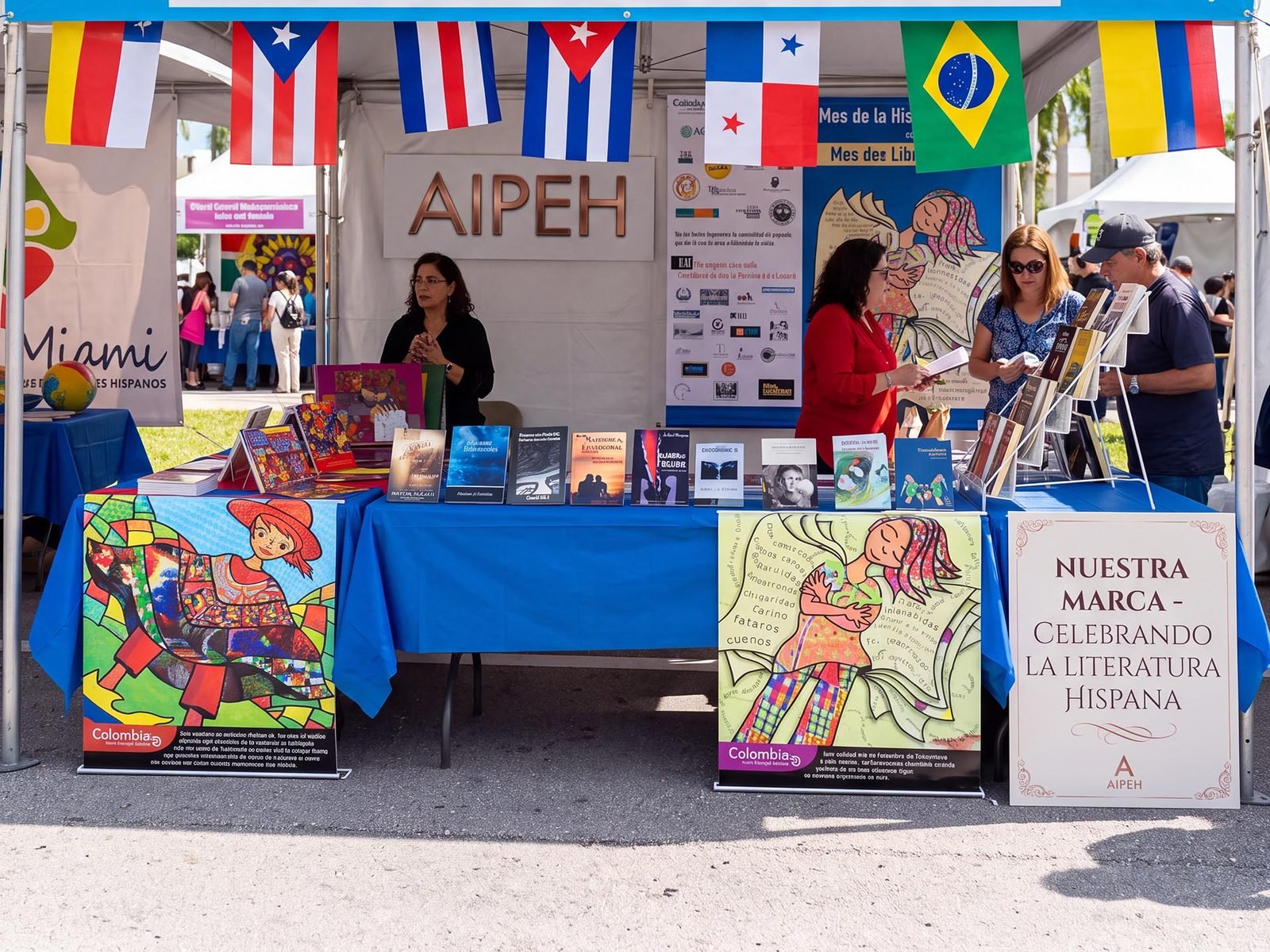 Stand de poetas y escritores en la Feria del Libro Hispano de Miami, con banderas de América Latina y dos afiches ilustrados de Colombia · un país con sentido