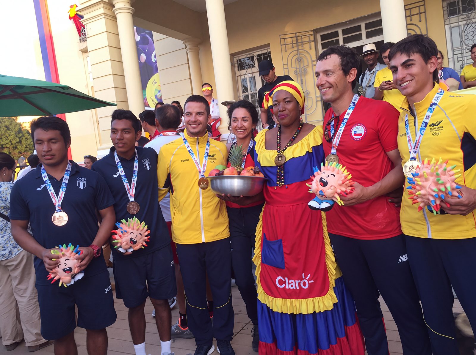 Deportistas con sus medallas junto a una cantadora en traje típico en Casa Colombia, durante los Juegos Bolivarianos de Santa Marta 2017
